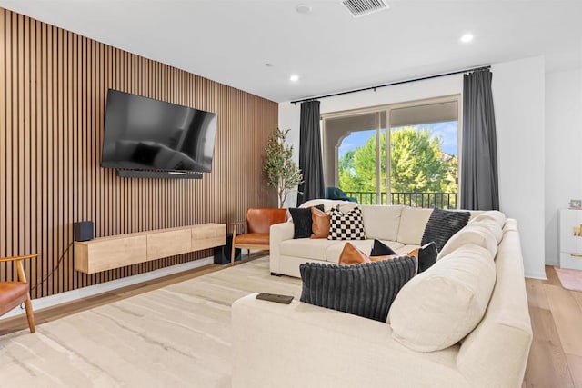 living area featuring recessed lighting, an accent wall, wood finished floors, visible vents, and baseboards