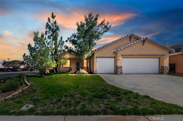 view of front of home featuring an attached garage, a yard, concrete driveway, stone siding, and stucco siding