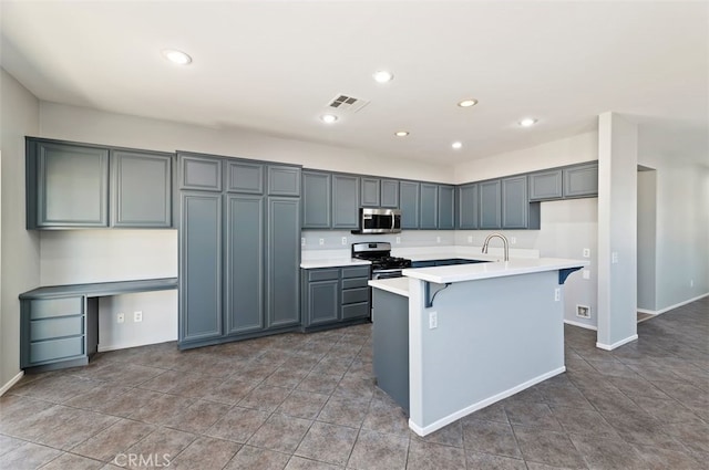 kitchen featuring a center island with sink, light countertops, visible vents, appliances with stainless steel finishes, and a kitchen bar