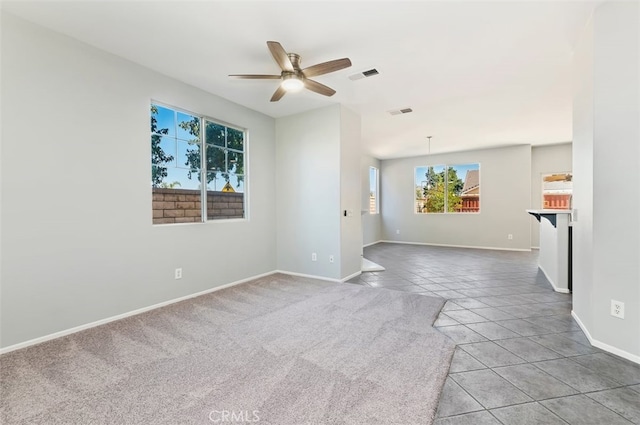 empty room featuring a ceiling fan, visible vents, baseboards, and light tile patterned floors