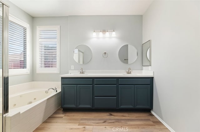 full bathroom with a sink, a tub with jets, and wood finished floors