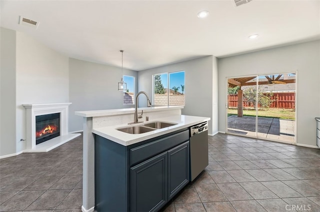 kitchen with light countertops, visible vents, a glass covered fireplace, a sink, and dishwasher