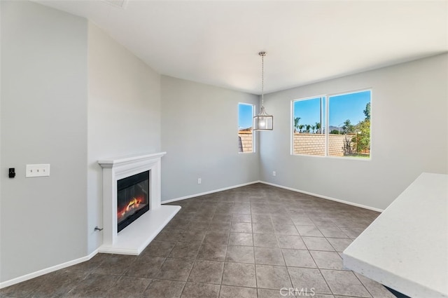 unfurnished living room with tile patterned floors, a glass covered fireplace, and baseboards