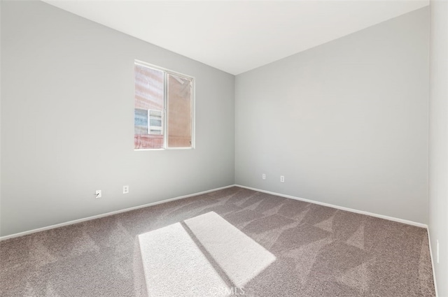 carpeted spare room featuring baseboards