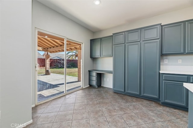 kitchen featuring light countertops, built in study area, baseboards, and light tile patterned flooring