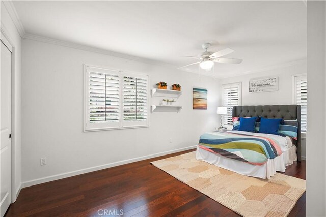 bedroom with baseboards, multiple windows, wood finished floors, and crown molding