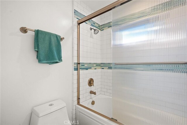 bathroom with toilet and bath / shower combo with glass door