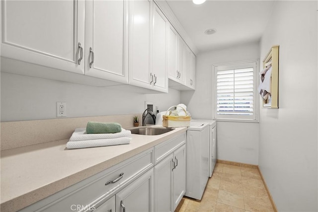 washroom featuring baseboards, cabinet space, independent washer and dryer, and a sink