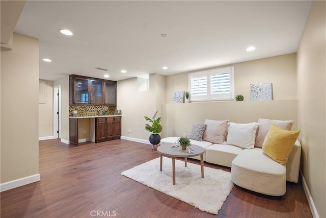 living room with dark wood finished floors, bar area, recessed lighting, and baseboards