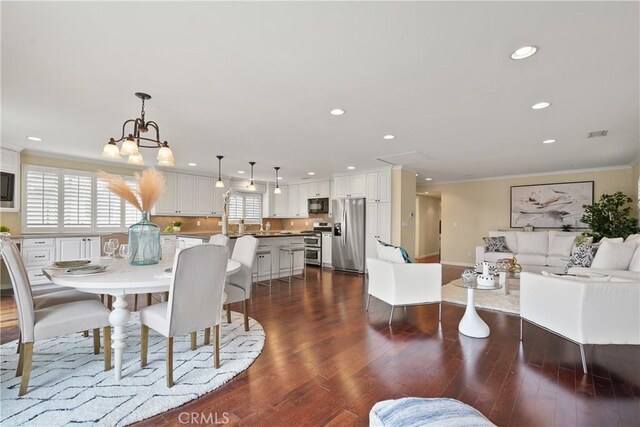 dining area featuring visible vents, dark wood finished floors, ornamental molding, recessed lighting, and a notable chandelier