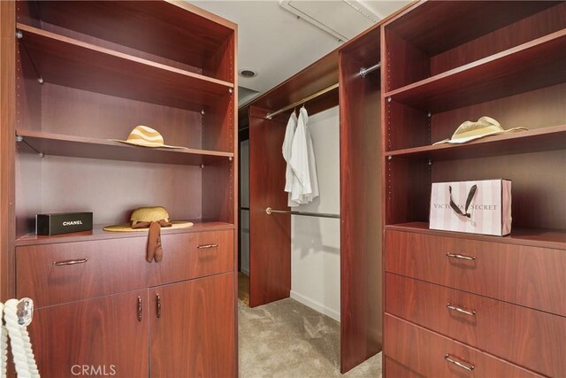 walk in closet featuring light colored carpet