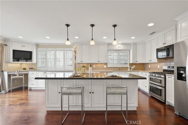 kitchen featuring white cabinetry, decorative backsplash, a breakfast bar area, and stainless steel appliances