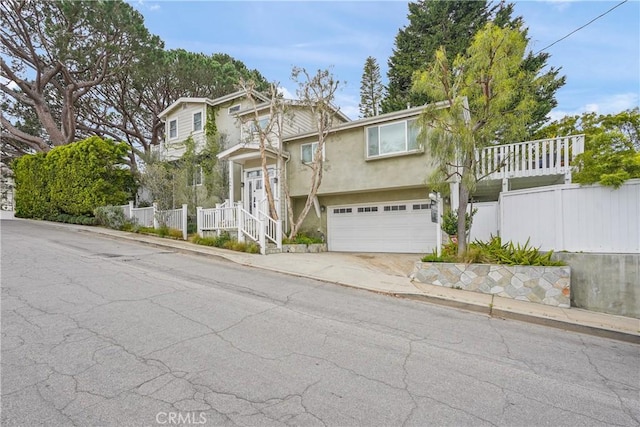 view of front of property featuring an attached garage, fence, driveway, and stucco siding