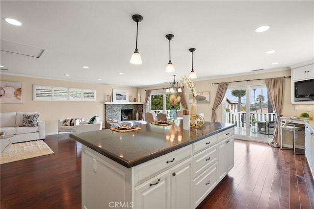 kitchen with dark countertops, a healthy amount of sunlight, dark wood-type flooring, and ornamental molding