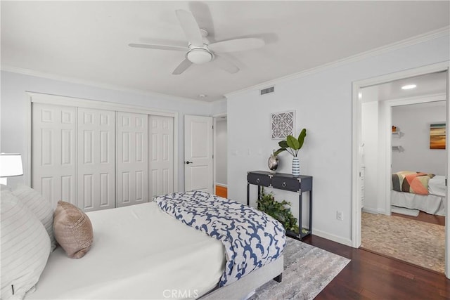 bedroom with a closet, visible vents, dark wood-style floors, and ornamental molding