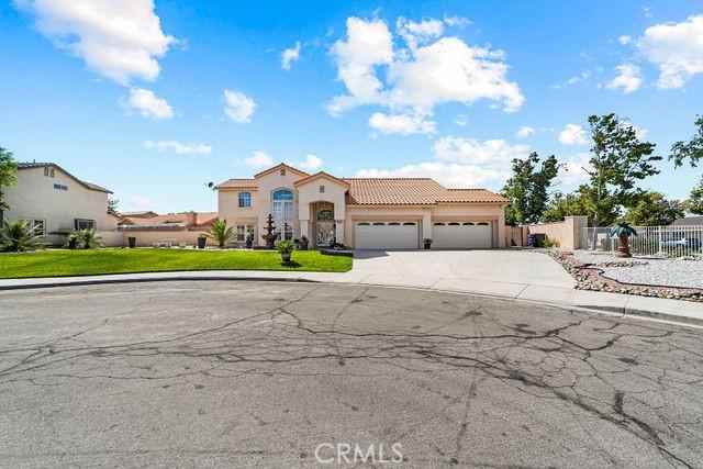 mediterranean / spanish-style home with a garage, a tiled roof, concrete driveway, and fence