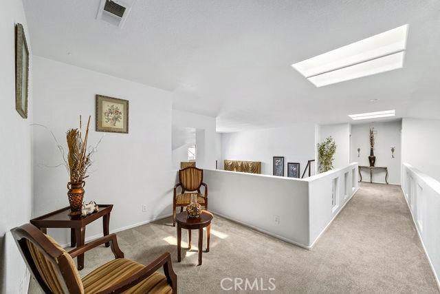 living area featuring a skylight, visible vents, and light colored carpet