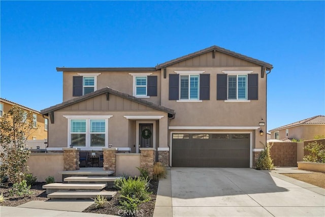 view of front of home featuring an attached garage, fence, driveway, stone siding, and stucco siding