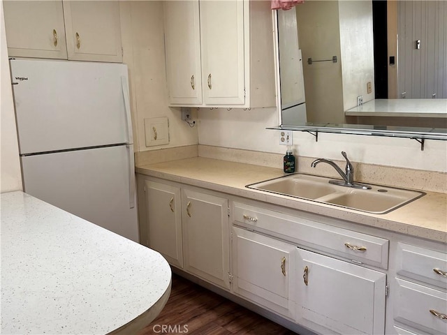 kitchen featuring a sink, white cabinets, light countertops, freestanding refrigerator, and dark wood finished floors