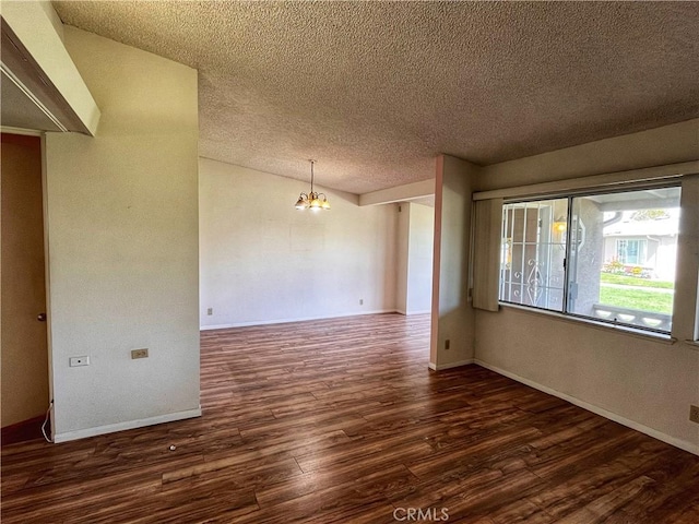 unfurnished room featuring a chandelier, a textured ceiling, wood finished floors, and baseboards