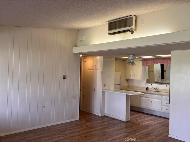 kitchen with a wall mounted air conditioner, light countertops, dark wood-type flooring, and freestanding refrigerator