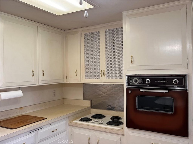 kitchen featuring light countertops, white electric stovetop, oven, and white cabinetry