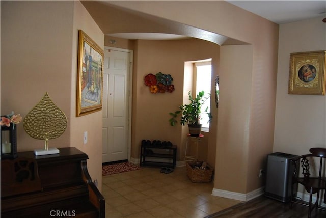 foyer with arched walkways and baseboards