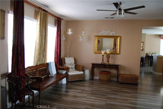 living area with baseboards, ceiling fan, visible vents, and wood finished floors