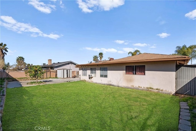 back of property with a fenced backyard, an outdoor structure, a yard, stucco siding, and a shed