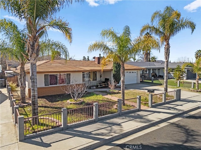 single story home featuring driveway, brick siding, a fenced front yard, an attached garage, and stucco siding