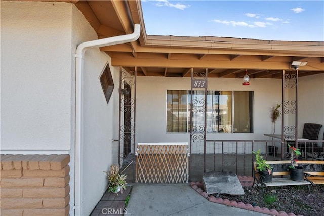 view of exterior entry with a porch and stucco siding