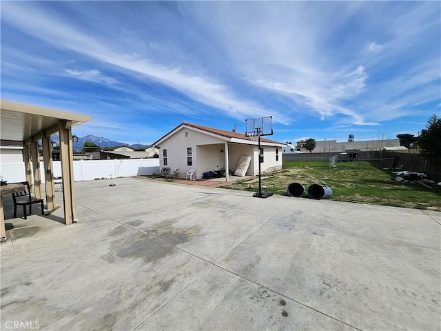 exterior space featuring stucco siding, a fenced backyard, a patio, and a yard