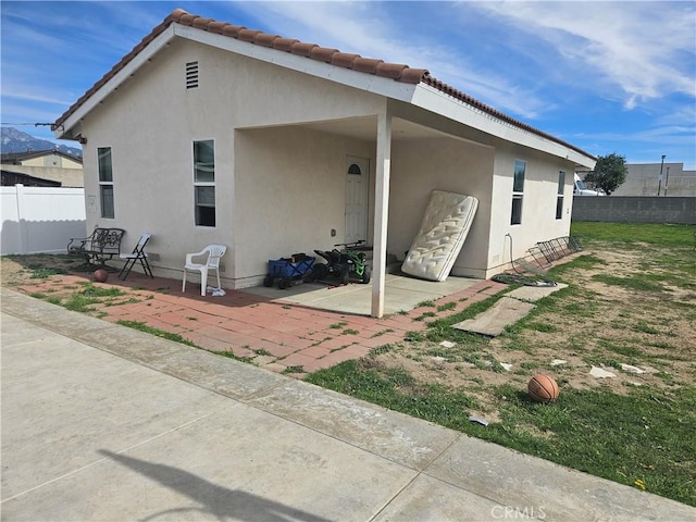 back of property with a patio area, a tile roof, fence, and stucco siding