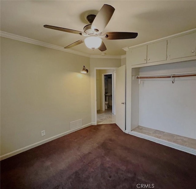 unfurnished bedroom with ornamental molding, dark colored carpet, a closet, and visible vents