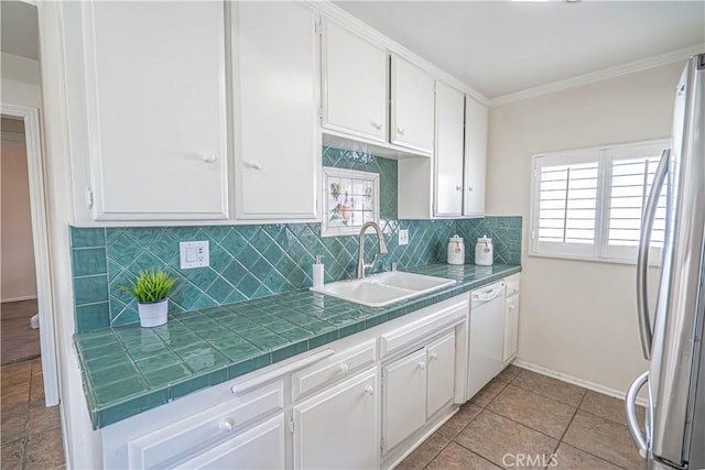 kitchen featuring tile counters, freestanding refrigerator, white cabinets, white dishwasher, and a sink