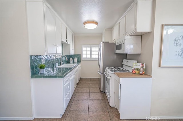 kitchen featuring white appliances, tasteful backsplash, baseboards, white cabinetry, and a sink