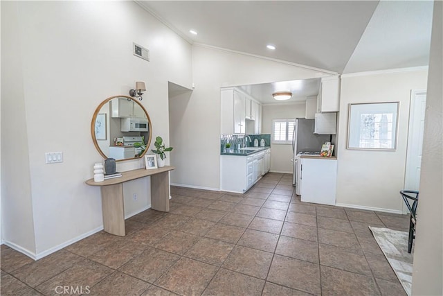 kitchen with visible vents, lofted ceiling, white microwave, ornamental molding, and a sink