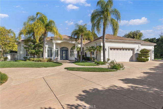 mediterranean / spanish house with a garage, a front yard, driveway, and stucco siding