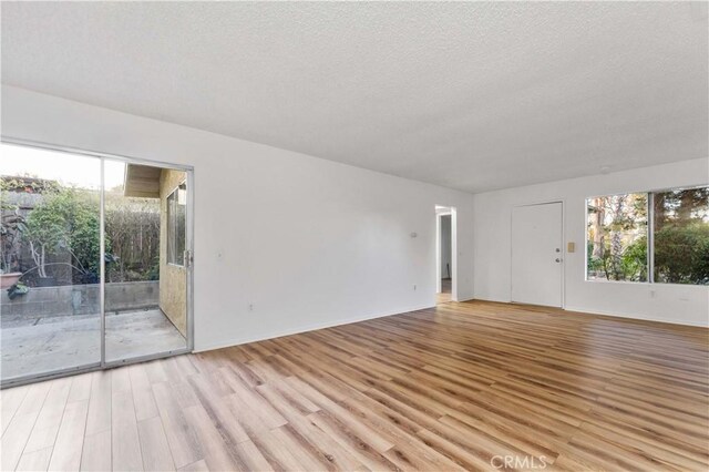 4738 Knoll Wood Ct, Oceanside, CA 92056 - empty room with wood finished floors, plenty of natural light, a textured ceiling, and baseboards