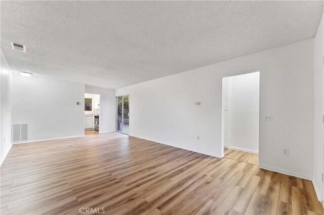 4738 Knoll Wood Ct, Oceanside, CA 92056 - unfurnished living room featuring a textured ceiling, light wood finished floors, and baseboards