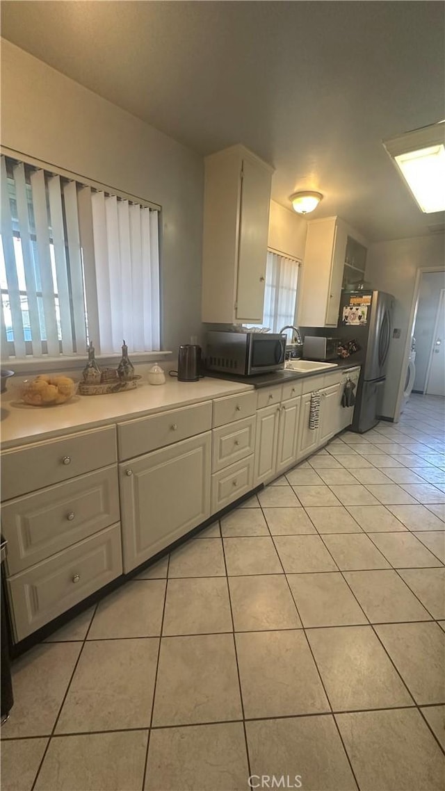 kitchen with stainless steel appliances, light countertops, white cabinets, light tile patterned flooring, and a sink