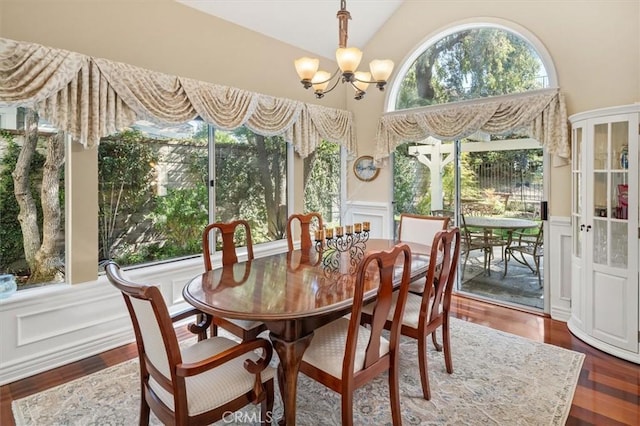 dining space with dark wood-style flooring, a wainscoted wall, high vaulted ceiling, a decorative wall, and a chandelier