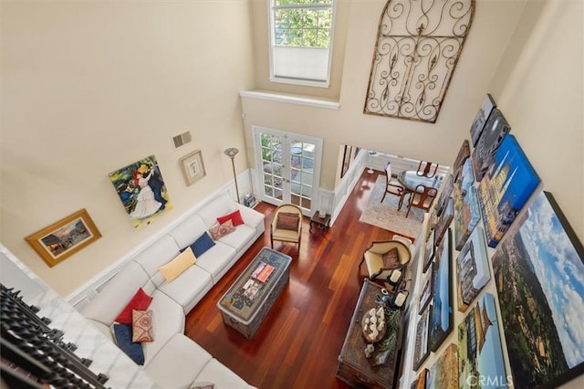 living room with a high ceiling, visible vents, wood finished floors, and french doors