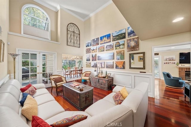 living area featuring a fireplace, wood finished floors, ornamental molding, french doors, and wainscoting