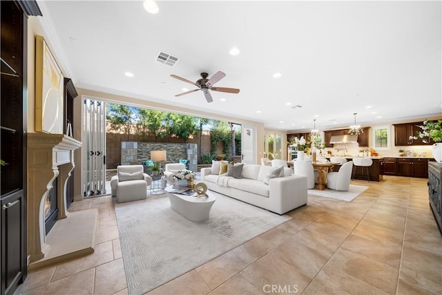 living area featuring plenty of natural light, a glass covered fireplace, visible vents, and crown molding