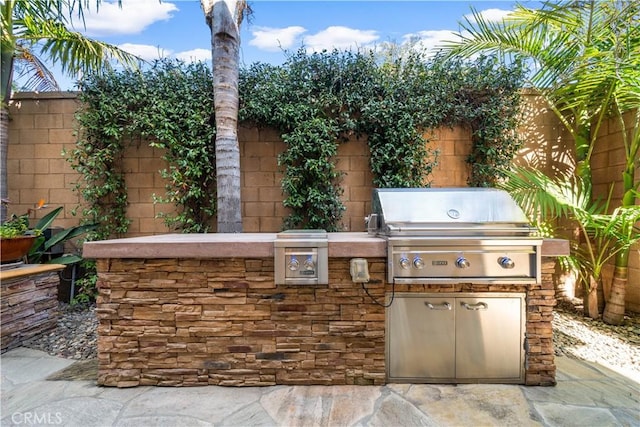 view of patio featuring an outdoor kitchen, a fenced backyard, and grilling area