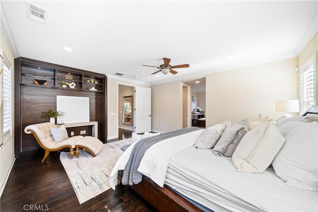 bedroom with dark wood-style flooring, visible vents, crown molding, and baseboards