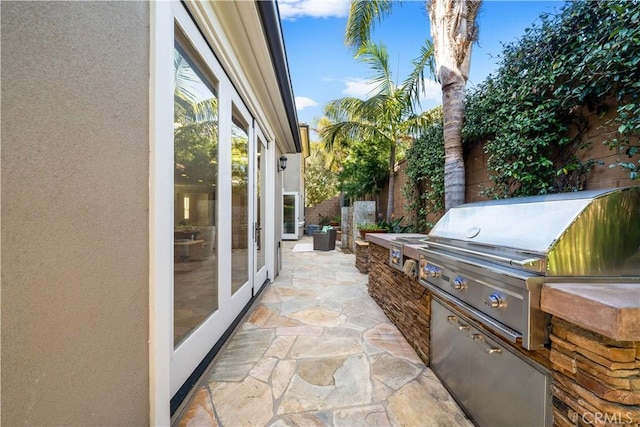 view of patio / terrace featuring exterior kitchen, grilling area, and fence