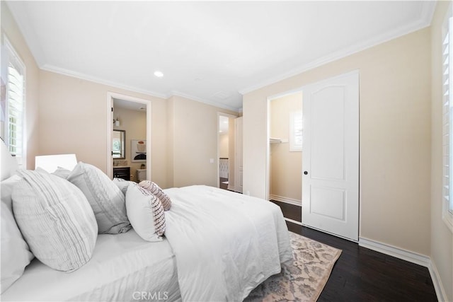 bedroom with ensuite bathroom, dark wood-style flooring, baseboards, a walk in closet, and crown molding