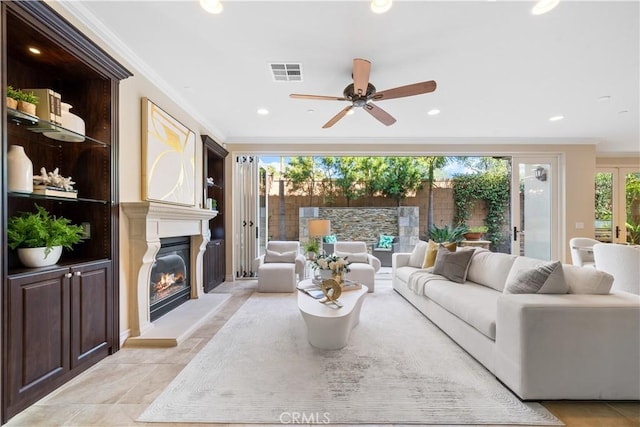 living area with ornamental molding, a glass covered fireplace, visible vents, and recessed lighting